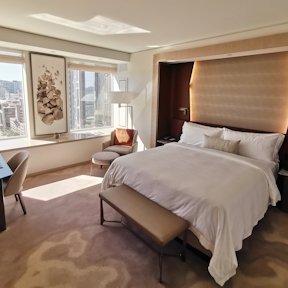 Suite de hotel con cama king size, cabecero de madera, alfombra beige y luz natural desde la ventana