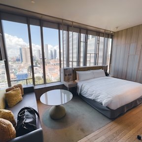 Habitación con cama doble y ventanales panorámicos con vista a la ciudad, decoración moderna en tonos grises